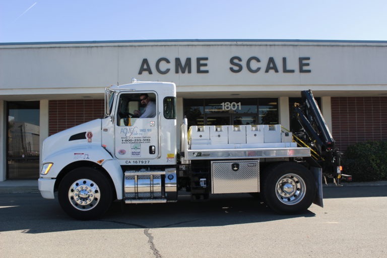 semi truck with scales in the back parked in front of acme scale company